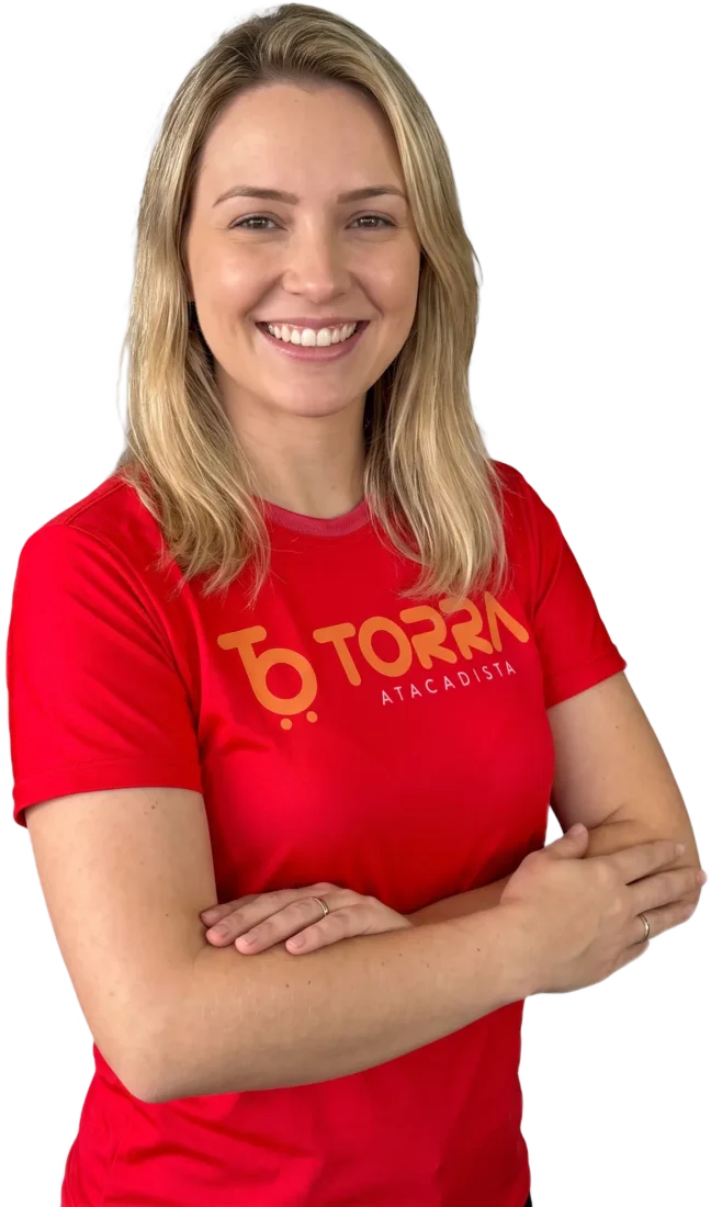 Colaboradora do Torra sorrindo, de braços cruzados, com a camisa vermelha da loja
